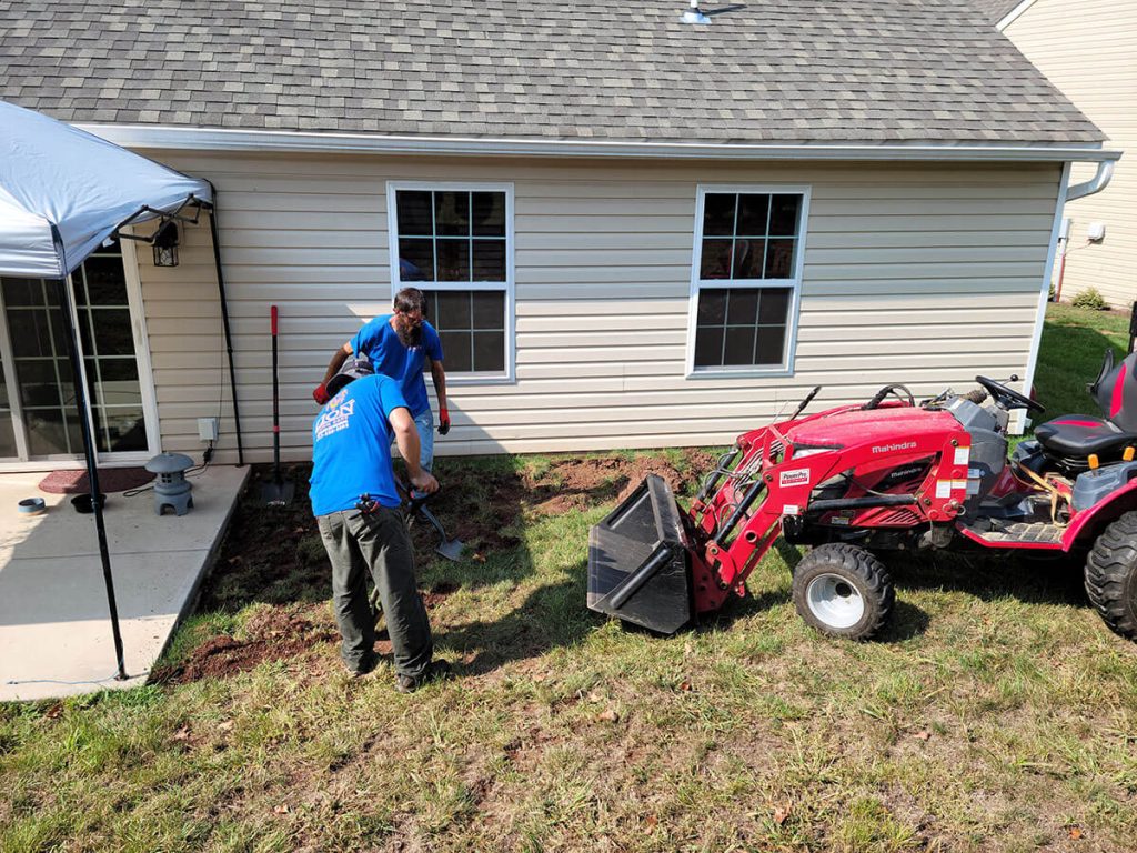 landscaping professionals using landscaping equipment outside of white home