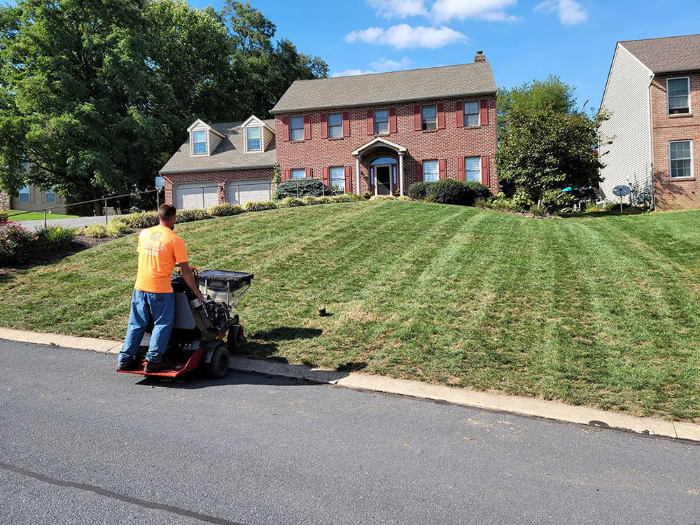 lawn mowing professional mowing lawn in front of brick home