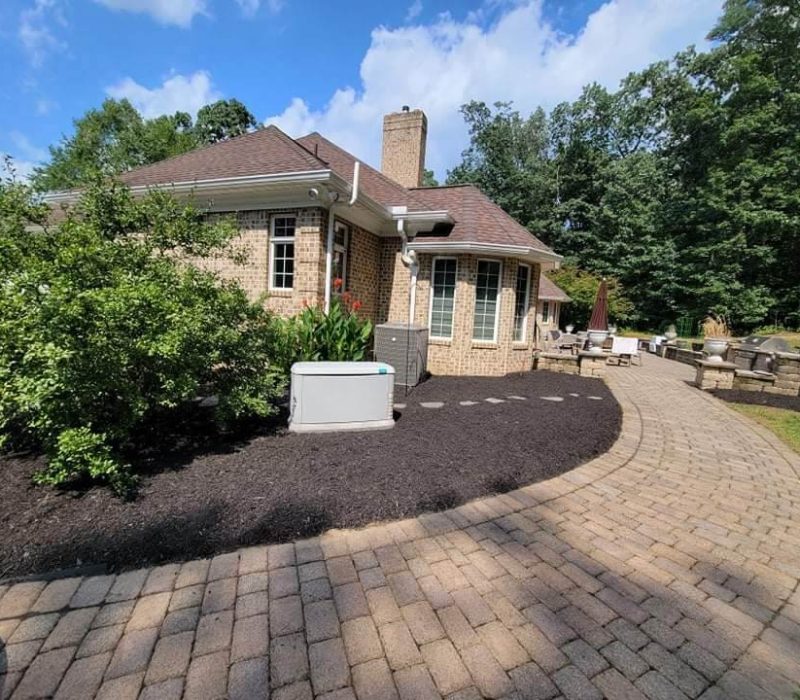 brick home with paved walkway and mulch area