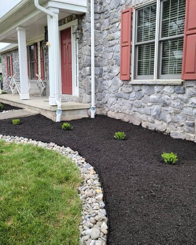 gray stone home with mulch and plants