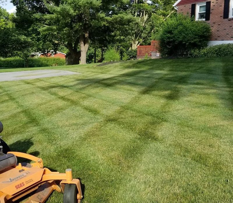 mowed lawn by brick home with yellow mower