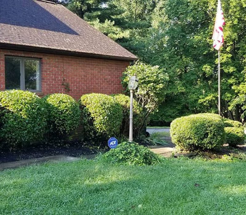brick home with bushes and flag